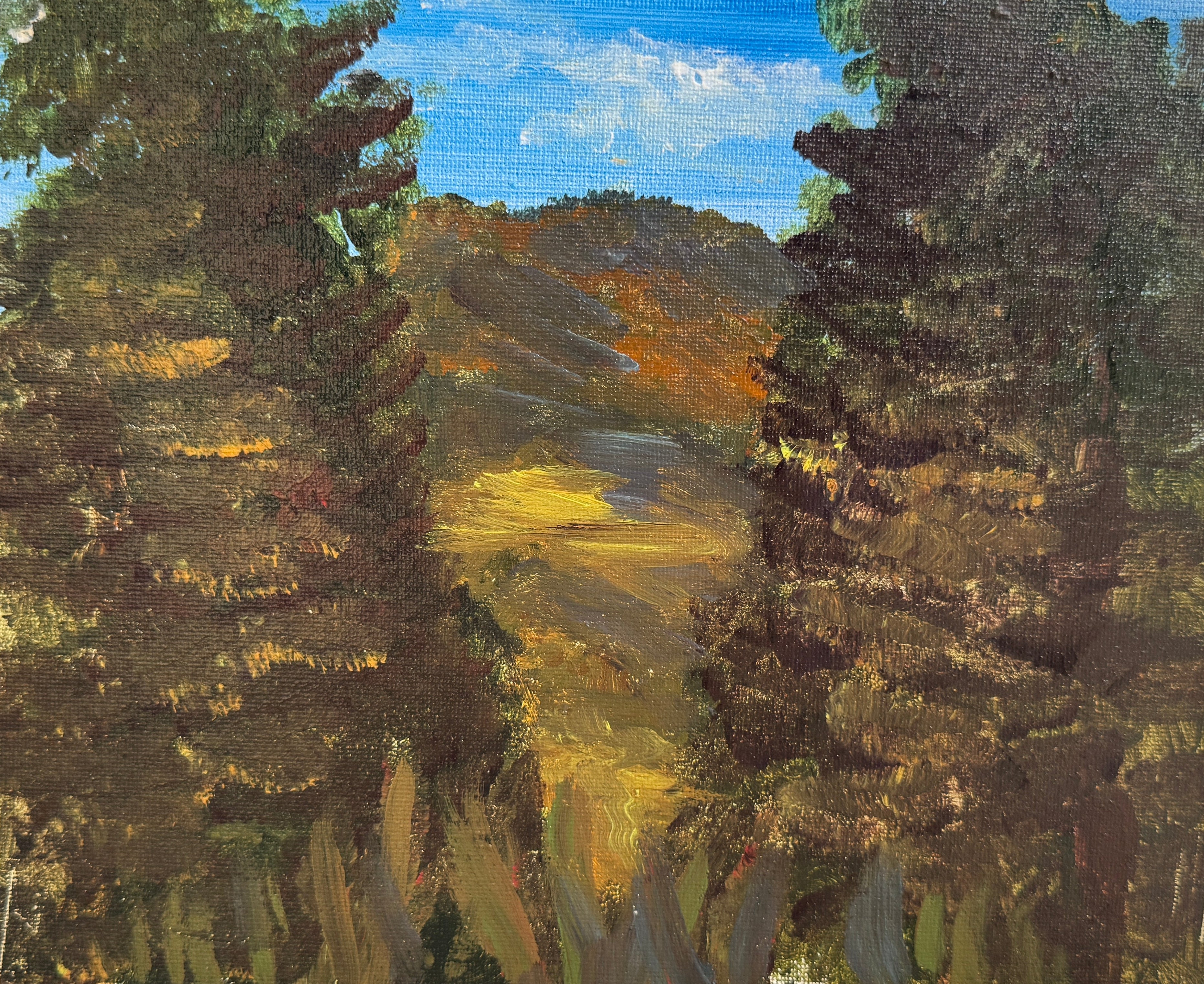 Small landscape painting with trees and a field on a wooden panel.